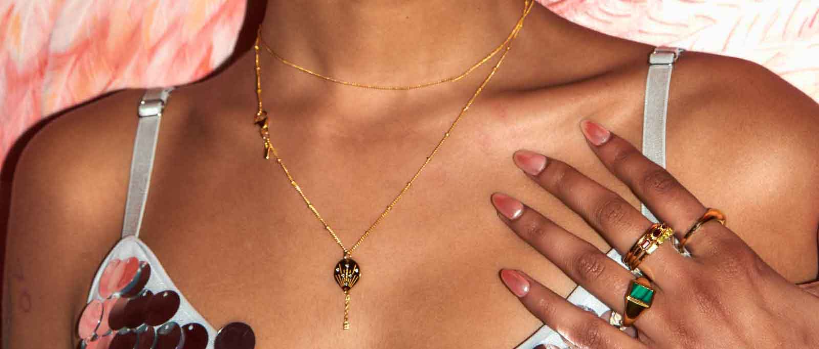 Attractive model wears ALASALWA Gold Vermeil Jewelry including post dangle earrings, gold vermeil necklace, and gold vermeil rings with stones.
